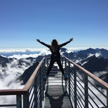 Woman is opening her arms while on top of a mountain